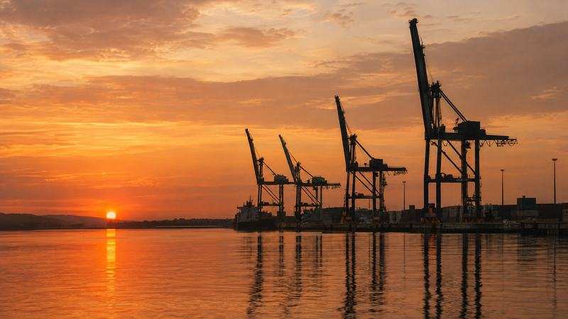 Port quay cranes silhouetted at golden dusk