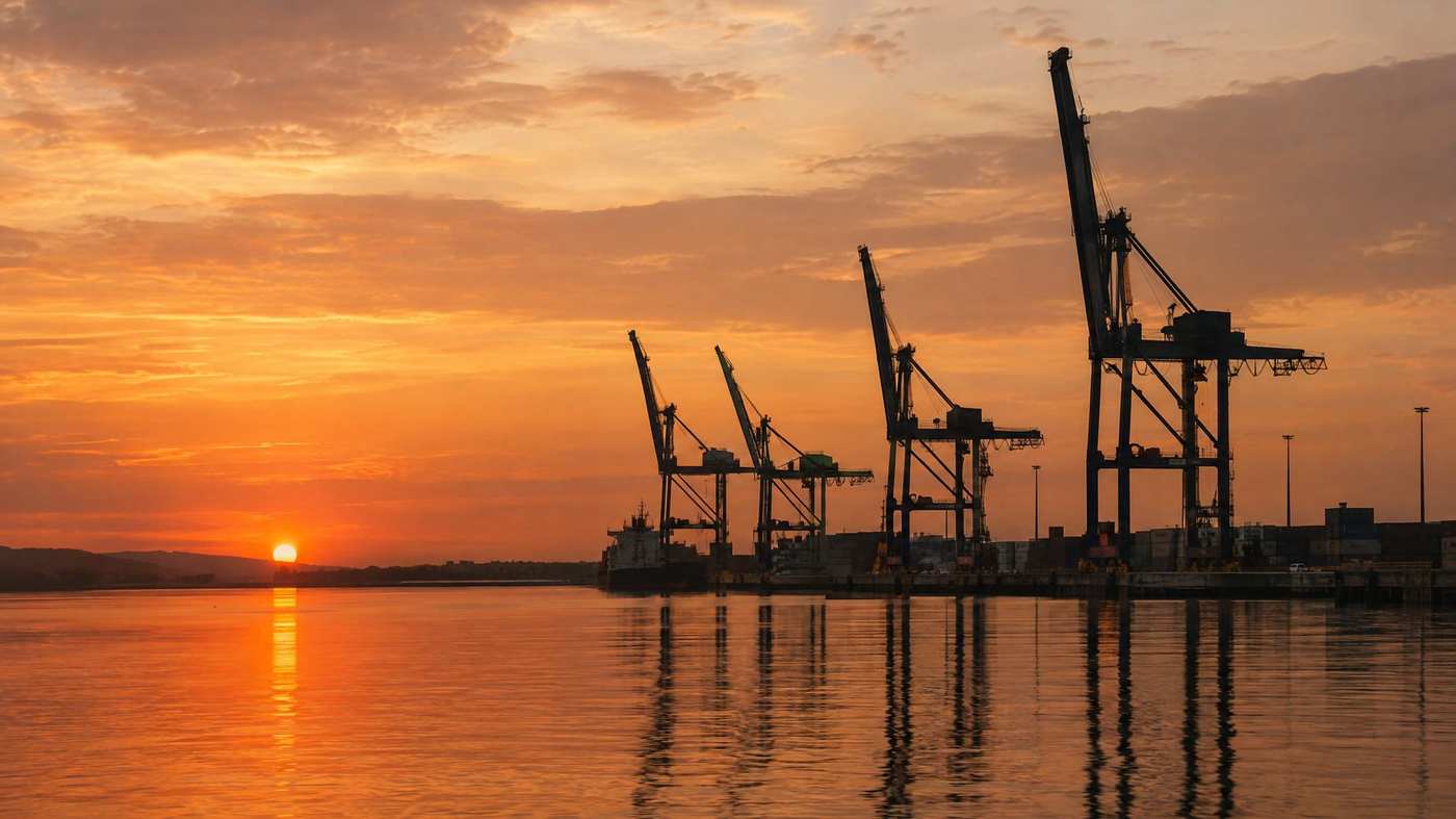 Port quay cranes silhouetted at golden dusk