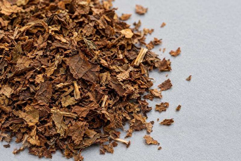 Close view of dark-brown coarse tobacco scrap pieces