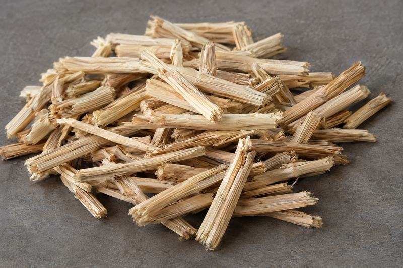 A heap of short pale woody tobacco stems on a grey surface