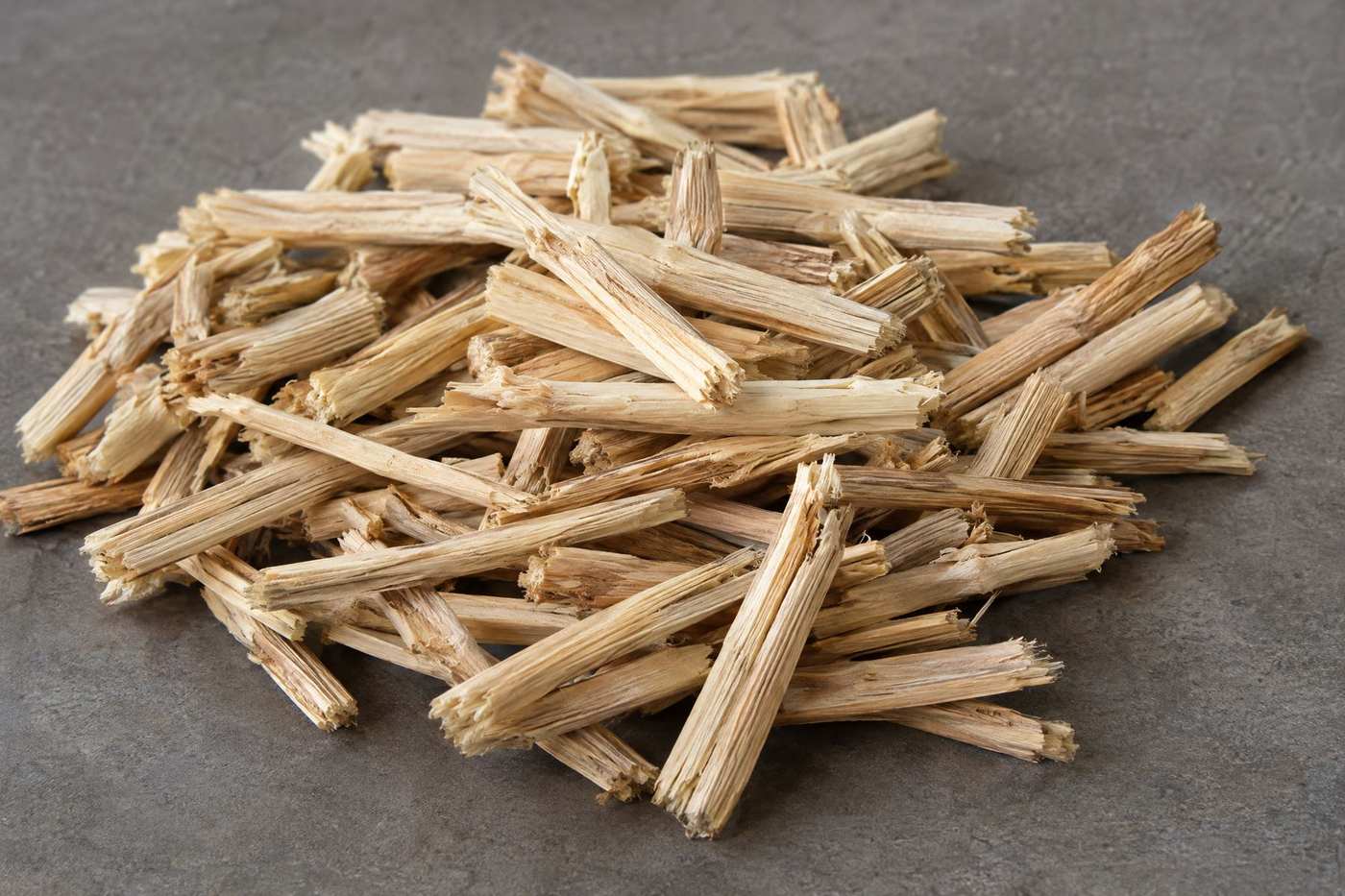 A heap of short pale woody tobacco stems on a grey surface